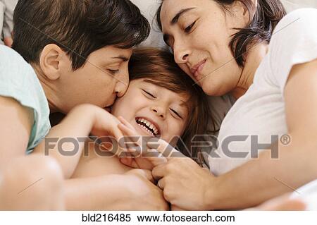 Stock Photography - Caucasian family cuddling in bed. Fotosearch