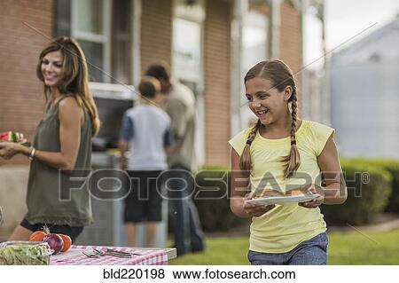Stock Photo - Caucasian family eating in backyard. Fotosearch