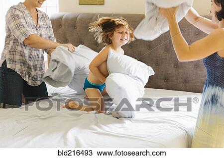 Stock Image - Caucasian family having pillow fight in bedroom. Fotosearch