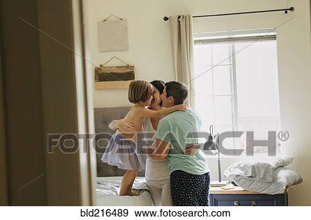 Stock Photo - Caucasian family hugging in bedroom. Fotosearch