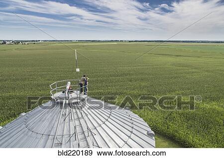 Stock Photo - Caucasian farmer and son admiring farm from silo. Fotosearch