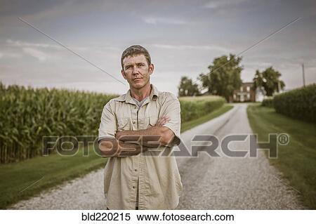 Caucasian farmer standing on dirt road by corn field View Large Photo Image Stock Photography - Caucasian farmer standing on dirt road by corn field. Fotosearch