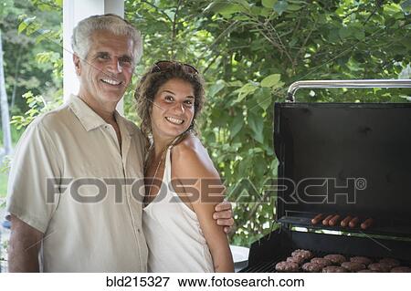 Stock Photo - Caucasian father and daughter grilling in backyard. Fotosearch
