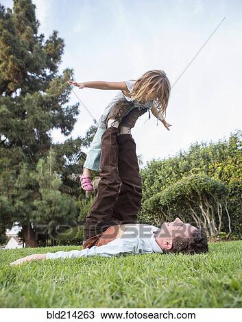 Caucasian father and daughter playing in grass View Large Photo Image Stock Image - Caucasian father and daughter playing in grass. Fotosearch