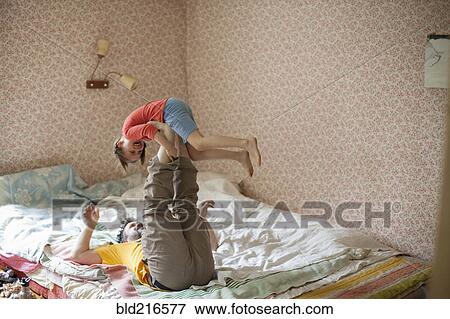 Caucasian father and daughter playing on bed View Large Photo Image Stock Photo - Caucasian father and daughter playing on bed. Fotosearch