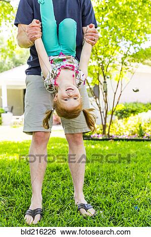 Stock Photograph - Caucasian father and daughter playing in backyard. Fotosearch