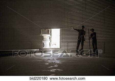 Stock Image - Caucasian father and on standing in empty silo. Fotosearch
