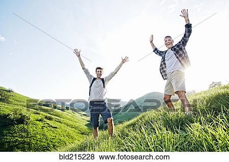 Caucasian father and son cheering on grassy hillside View Large Photo Image Stock Photo - Caucasian father and son cheering on grassy hillside. Fotosearch