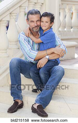 Stock Photo - Caucasian father and son hugging on front stoop. Fotosearch