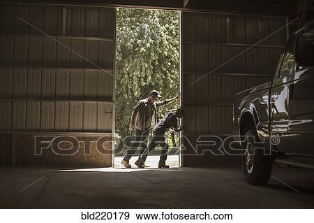 Stock Photo - Caucasian father and son opening barn door. Fotosearch