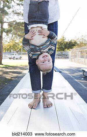 Stock Image - Caucasian father and son playing on picnic table. Fotosearch
