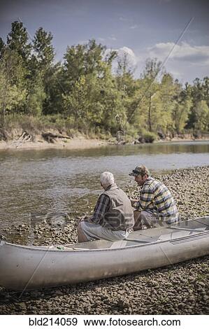 Caucasian father and son sitting in canoe on riverbed View Large Photo Image Stock Photo - Caucasian father and son sitting in canoe on riverbed. Fotosearch