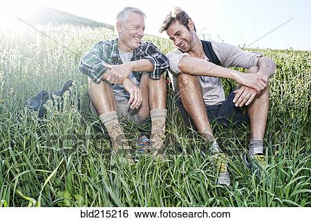 Caucasian father and son sitting on grassy hillside View Large Photo Image Stock Photograph - Caucasian father and son sitting on grassy hillside. Fotosearch