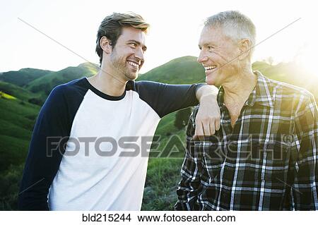 Picture - Caucasian father and son smiling on rural hilltop. Fotosearch