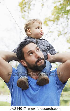 Stock Photo - Caucasian father carrying baby son outdoors. Fotosearch