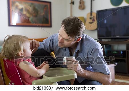 Stock Photo - Caucasian father feeding toddler daughter. Fotosearch