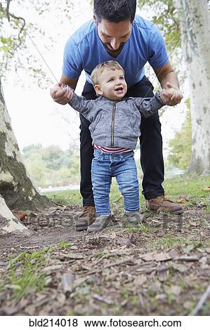 Caucasian father helping baby son walk outdoors View Large Photo Image Stock Photo - Caucasian father helping baby son walk outdoors. Fotosearch