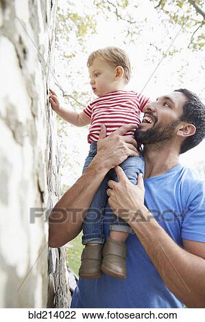 Caucasian father holding baby son under tree View Large Photo Image Stock Image - Caucasian father holding baby son under tree. Fotosearch