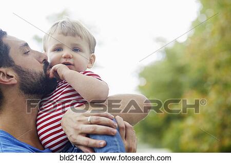 Stock Image - Caucasian father kissing baby son. Fotosearch