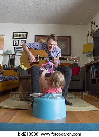 Stock Photo - Caucasian father playing guitar for daughter. Fotosearch