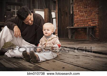 Stock Photo - Caucasian father sitting on floor with son. Fotosearch