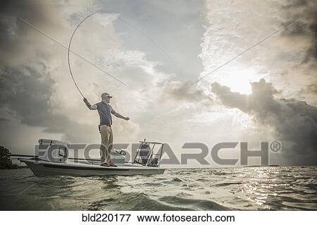 Stock Photo - Caucasian fisherman casting line from boat. Fotosearch