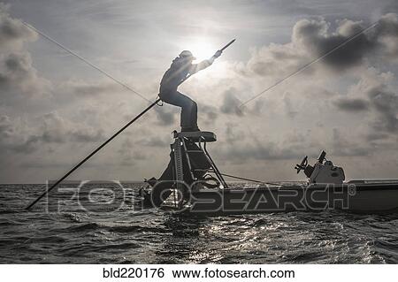 Stock Photograph - Caucasian fisherman rowing boat on ocean. Fotosearch