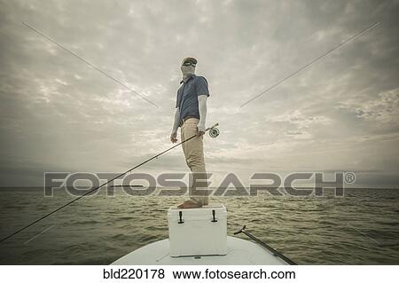 Stock Photo - Caucasian fisherman standing on boat. Fotosearch