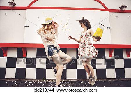 Picture - Caucasian friends having popcorn fight outdoors. Fotosearch