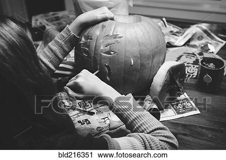 Stock Image - Caucasian girl carving jack-o-lantern pumpkin. Fotosearch