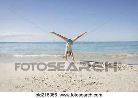 Stock Photograph - Caucasian girl doing cartwheel on beach. Fotosearch