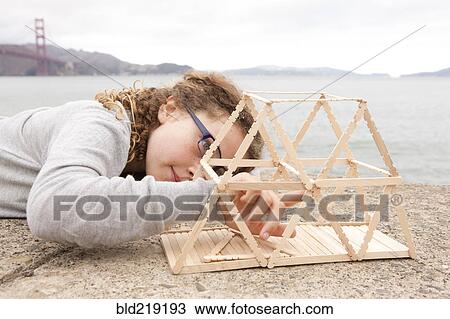 Stock Image - Caucasian girl examining project on wall over ocean. Fotosearch