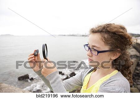 Caucasian girl examining stone with magnifying glass View Large Photo Image Stock Photograph - Caucasian girl examining stone with magnifying glass. Fotosearch