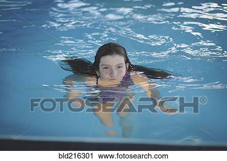 Stock Image - Caucasian girl floating in swimming pool. Fotosearch