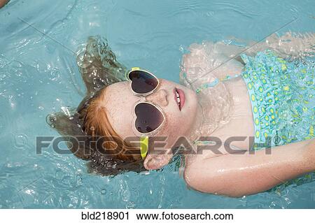 Stock Image - Caucasian girl floating in swimming pool. Fotosearch