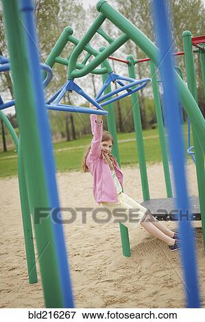 Caucasian girl hanging from structure in playground View Large Photo Image Stock Photo - Caucasian girl hanging from structure in playground. Fotosearch
