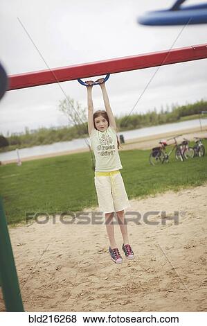 Caucasian girl hanging from structure in playground View Large Photo Image Stock Photo - Caucasian girl hanging from structure in playground. Fotosearch