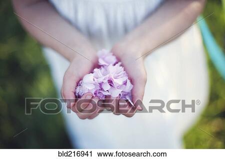 Stock Image - Caucasian girl holding flower petals. Fotosearch