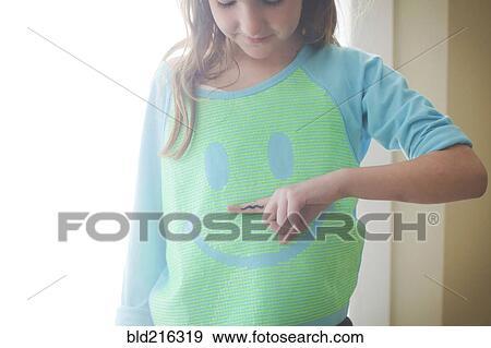 Stock Photo - Caucasian girl holding mustache over smiley face shirt. Fotosearch