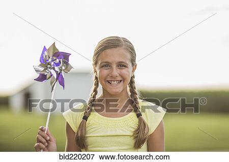 Stock Photo - Caucasian girl holding pinwheel on farm. Fotosearch