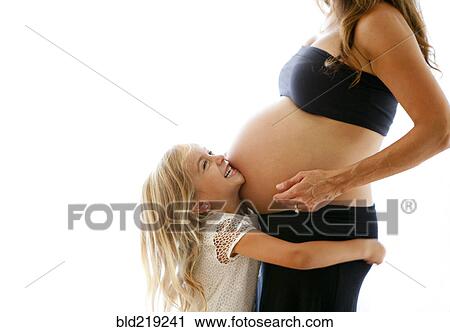 Stock Image - Caucasian girl hugging pregnant mother. Fotosearch