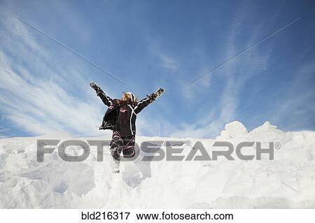Stock Photo - Caucasian girl jumping on snowy hillside. Fotosearch