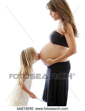Stock Image - Caucasian girl kissing belly of pregnant mother. Fotosearch