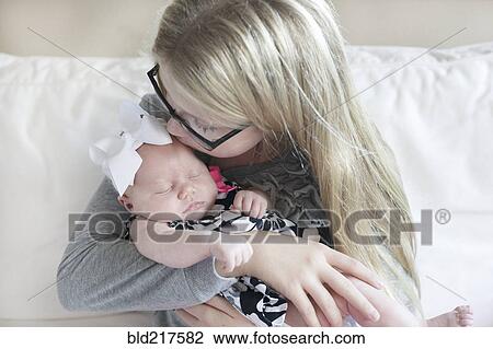 Caucasian girl kissing newborn sister on sofa View Large Photo Image Stock Image - Caucasian girl kissing newborn sister on sofa. Fotosearch