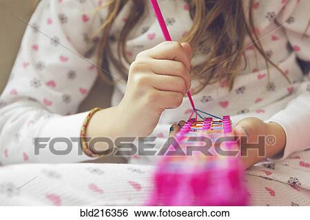 Stock Photograph - Caucasian girl knitting with rainbow loom. Fotosearch