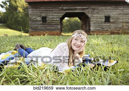 Caucasian girl laying in grass on farm View Large Photo Image Stock Photo - Caucasian girl laying in grass on farm. Fotosearch