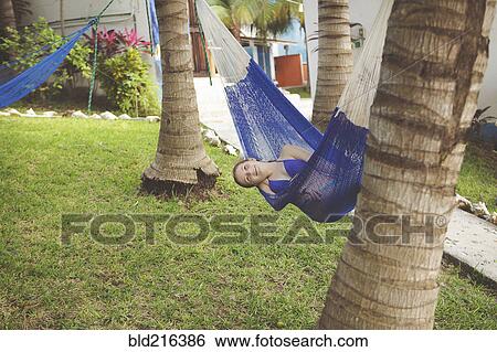 Stock Photograph - Caucasian girl laying in hammock in backyard. Fotosearch
