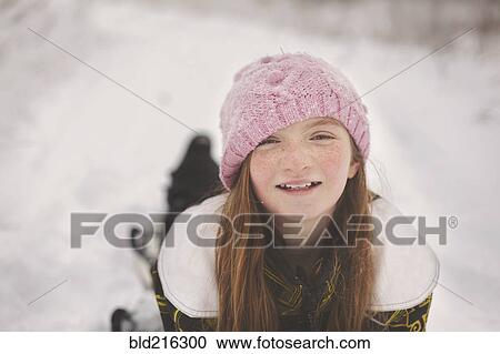 Stock Image - Caucasian girl laying in snow. Fotosearch