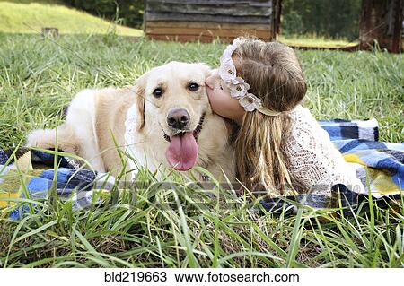 Stock Image - Caucasian girl laying on blanket with dog. Fotosearch