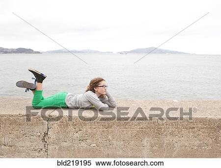 Caucasian girl laying on concrete wall over ocean View Large Photo Image Stock Photography - Caucasian girl laying on concrete wall over ocean. Fotosearch